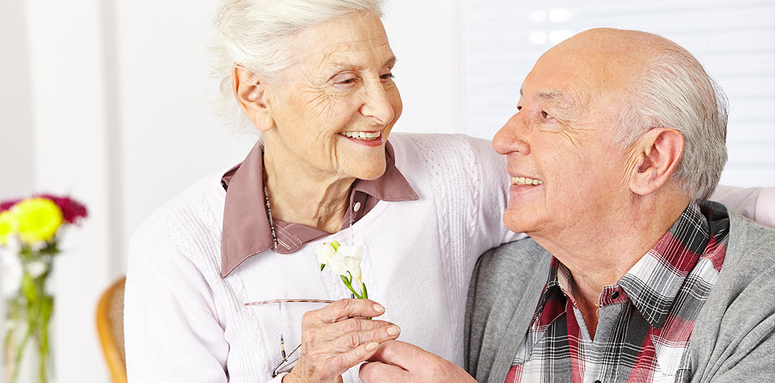 elder couple smile over a flower