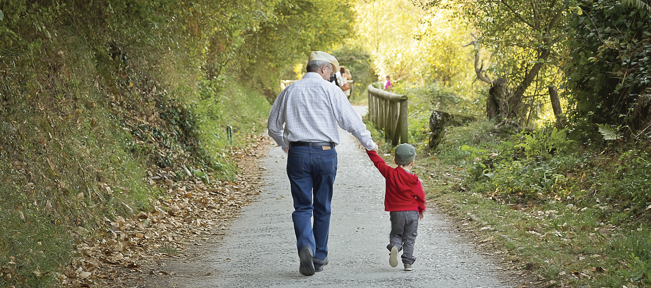 grandpa holds grandson's hand on a walk