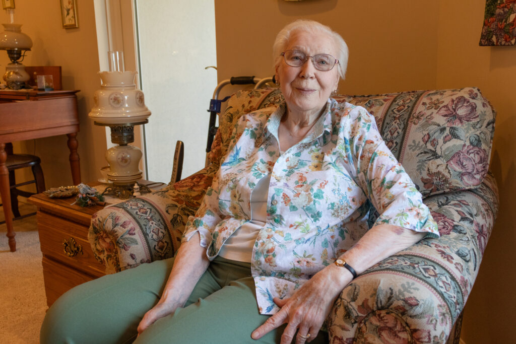 Jean Lacey A woman sits in a comfy armchair in her home.